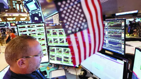 FILE PHOTO: A trader works at the New York Stock Exchange (NYSE) next to a U.S. flag, after Republican Donald Trump won the U.S. presidential election, in New York City, U.S., November 6, 2024. REUTERS/Andrew Kelly/File Photo