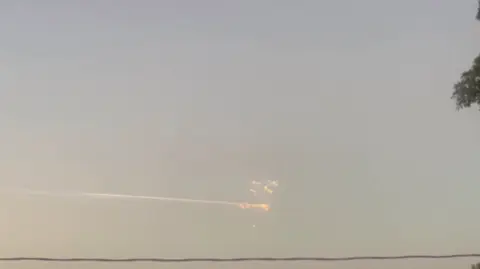 Bolas de luz anaranjadas vuelan por el cielo dejando una estela de humo a su paso, mientras los restos de un cohete SpaceX lanzado desde Texas se ven sobre Puerto Príncipe, Haití.