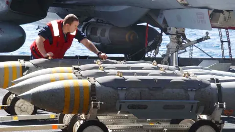 Un operario de artillería de aviación mueve bombas de 2,000 libras configuradas como Municiones de Ataque Directo Conjunto (JDAM) MK-84