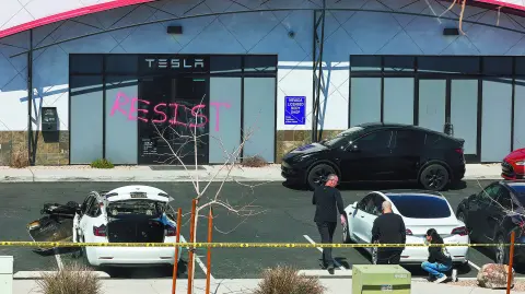LAS VEGAS, NEVADA - MARCH 18: Investigators look over the scene at a Tesla Collision Center after an individual used incendiary devices to set several vehicles on fire on March 18, 2025 in Las Vegas, Nevada. The Las Vegas Metropolitan Police Department said that five Teslas were damaged and believe that the suspect fired three rounds from a firearm at the vehicles and spray painted the word "RESIST" on the entrance.   Ethan Miller/Getty Images/AFP (Photo by Ethan Miller / GETTY IMAGES NORTH AMERICA / Getty Images via AFP)
