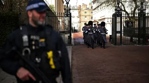 Un policía armado de guardia mientras los soldados se alejan de Clarence House, en el centro de Londres.