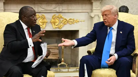 El presidente estadounidense Donald Trump entrega documentos al presidente sudafricano Cyril Ramaphosa durante una reunión en la Oficina Oval de la Casa Blanca en Washington.