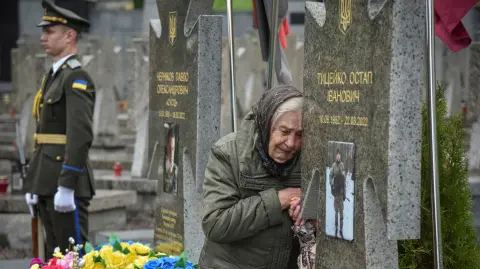 Una mujer reacciona mientras visita la tumba de su pariente, durante la conmemoración del Día de los Héroes, en el cementerio Lychakiv en Lviv, Ucrania.