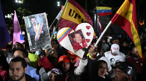 Partidarios del gobierno sostienen retratos del presidente venezolano Nicolás Maduro y del fallecido presidente venezolano Hugo Chávez.