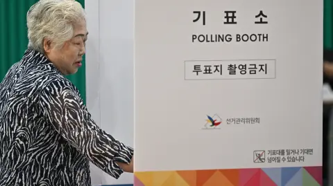 A woman enters a polling booth as he votes during the presidential election in Seoul on June 3, 2025. Polls opened June 3rd for South Korea's snap presidential election, with the country voting to choose a new leader after ex-president Yoon Suk Yeol was impeached over his abortive declaration of martial law."We were the first to arrive with the hope our candidate gets elected, and because the presidential election is the most important," Yu Bun-dol, 80, told AFP after lining up at 6:00 am (2100 GMT) to vote at a polling station in Seoul's Munrae-dong area. (Photo by Pedro Pardo / AFP)