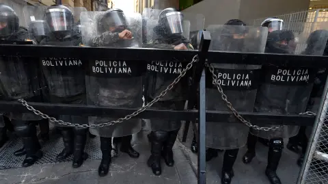 La policía antidisturbios de Bolivia vigila una de las entradas de la Plaza Murillo, mientras simpatizantes de Evo Morales protestan a favor de él.