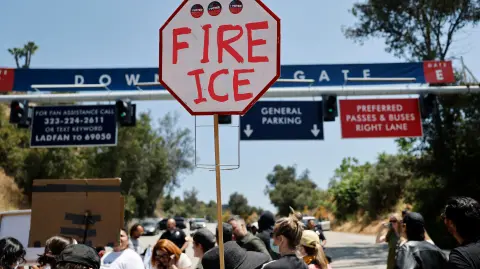 Manifestantes protestan cerca de agentes federales apostados frente a una puerta del Dodger Stadium.