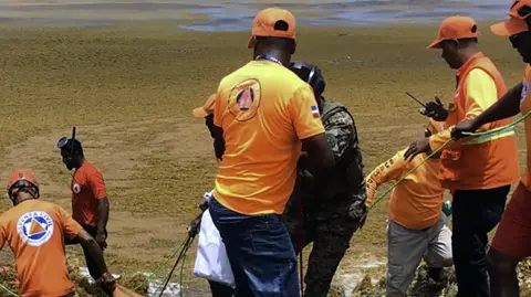Miembros de la Defensa Civil y la Armada recuperan el cuerpo de un náufrago.