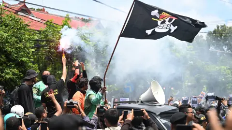 Manifestantes sostienen una bengala y ondean una bandera pirata del anime japonés One Piece, tendencia en internet utilizada para criticar las políticas gubernamentales.