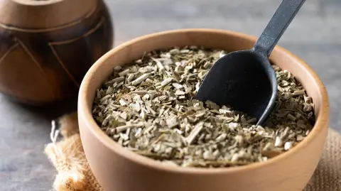 Traditional yerba mate in bowl on wooden table