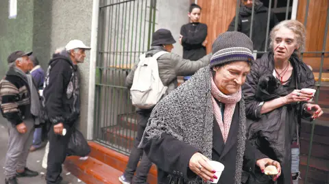 A woman walks away after receiving an afternoon snack from a church that helps the poor, as other people line up, in Buenos Aires, Argentina, May 31, 2024.