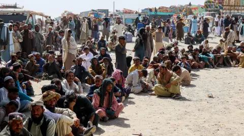 Ciudadanos afganos esperan para registrarse mientras intentan regresar a su país, con camiones cargados con sus pertenencias al fondo, después de que Pakistán cerrara los cruces fronterizos para el comercio con Afganistán.