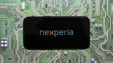 This photograph shows the Nexperia logo displayed on a smartphone, in Brussels on November 3, 2025. Nexperia is a semiconductor manufacturer headquartered in Nijmegen, the Netherlands. It is a subsidiary of Wingtech Technology, a Chinese company listed in Shanghai and partly owned by the Chinese government. (Photo by Nicolas TUCAT / AFP)