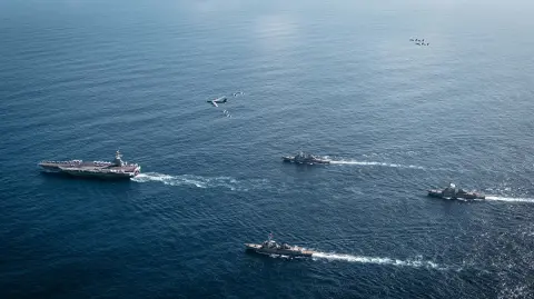 This handout from the US Department of Defense shows the US Navys Gerald R. Ford Carrier Strike Group, including the flagship USS Gerald R. Ford (CVN 78), left, USS Winston S. Churchill (DDG 81), front, USS Mahan (DDG 72), back, USS Bainbridge (DDG 96), and embarked Carrier Air Wing Eight F/A-18E/F Super Hornets assigned to Strike Fighter Squadrons 31, 37, 87, and 213, operates as a joint, multi-domain force with a US Air Force B-52 Stratofortress on November 13, 2025 at an undisclosed location in the Atlantic Ocean. The USS Gerald R. Ford, the world's largest aircraft carrier, entered an area under control of the US Naval Forces Southern Command, which encompasses Latin America and the Caribbean, the command said in a statement on November 11. (Photo by Tajh Payne / DoD / AFP) / RESTRICTED TO EDITORIAL USE - MANDATORY CREDIT "AFP PHOTO / DOD /   PETTY OFFICER 3RD CLASS TAJH PAYNE" - NO MARKETING NO ADVERTISING CAMPAIGNS - DISTRIBUTED AS A SERVICE TO CLIENTS