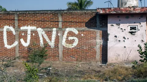 View of a bullet-riddled wall bearing the initials of the criminal group Cartel Jalisco Nueva Generacion (CJNG) at the entrance of the community of Aguililla, state of Michoacan, Mexico, on April 23, 2021. The municipality of Aguililla is being threatened due to the confrontation of organized crime groups called the Jalisco Nueva Generacion Cartel (CJNG) and the Michoacan Family (now called Viagras). (Photo by ENRIQUE CASTRO / AFP)