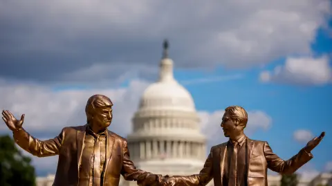La cúpula del Capitolio de los Estados Unidos es visible detrás de una estatua que representa al presidente estadounidense Donald Trump y a Jeffrey Epstein tomados de la mano.