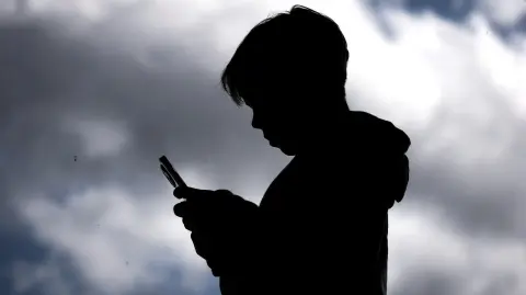 Chico de 14 años consultando redes sociales en su móvil.