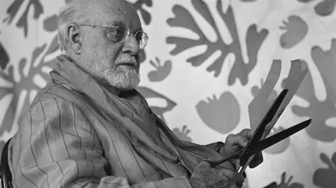 French painter and sculptor Henri Matisse cuts up gouache paper for his collage "The Parakeet and the Mermaid", still in progress, at his studio at the Hotel Regina in Nice, in July 1952. After studying law and working as a notary's clerk, Henri Matisse decided to devote himself to painting following an illness during which he had practiced painting. Decorative Arts, Fine Arts, copies at the Louvre and an interest in Muslim art led him to an eclectic career, from traditional to non-figurative, he was interested in Impressionism, took up sculpture, appeared as the leader of the "Fauves", practiced the technique of paper cutouts. His search for conciseness and simplicity culminated in the decoration of the chapel of Vence (1951). (Photo by AFP)