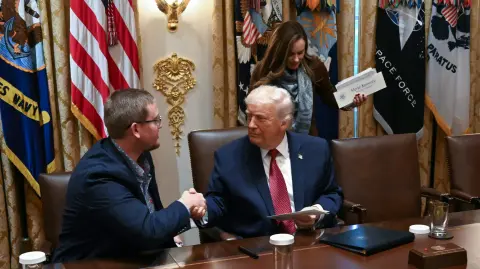 El presidente de Estados Unidos, Donald Trump, estrecha la mano de Cordt Holub, de NuTech Seed, al término de una mesa redonda para debatir la ayuda a los agricultores.