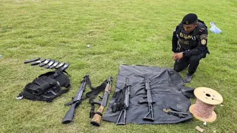 La fotografía muestra a un policía junto a armas y explosivos incautados en un operativo en la aldea Agua Zarca, Santa Ana Huista, Huehuetenango, Guatemala, el 8 de diciembre. Un enfrentamiento entre soldados guatemaltecos y un grupo armado mexicano que ingresó al territorio del país centroamericano dejó un muerto y un soldado herido el lunes.