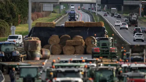 Vehicles leave the A64 motorway ahead of a farmers blockade in protest against health measures put in place to eradicate lumpy skin disease affecting cattle, in Carbonne, south-western France, on December 15, 2025. (Photo by Valentine CHAPUIS / AFP)