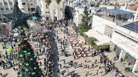 Una vista aérea muestra a los scouts marchando durante las celebraciones de la víspera de Navidad en la Plaza del Pesebre, afuera de la Iglesia de la Natividad (no vista) en Belén, en Cisjordania ocupada por Israel, el 24 de diciembre de 2025.