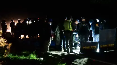 Miembros del Ministerio Público trabajan cerca de los cuerpos de las víctimas de un accidente de tránsito en Cumbre de Alaska en Totonicapán, Guatemala.