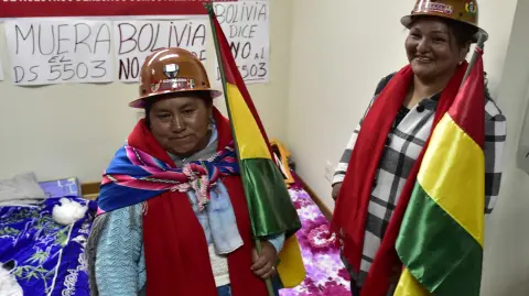 Beatriz Choque (L), member of the National Committee of Miners' Wives, speaks to the press alongside Miriam Huarina, wife of a miner, as they begin a hunger strike in support of a protest by miners affiliated with the country's largest trade union, Bolivian Workers' Central (COB), against the elimination of long-standing fuel subsidies by the government, at the headquarters of the Bolivian Mining Workers' Trade Union Federation (FSTMB) in La Paz on December 29, 2025. Bolivian miners -most of them affiliated with the Bolivian Workers' Central Union (COB)- took to the streets to protest against a decree by Rodrigo Paz's centre-right government on December 17 which doubled fuel prices and threatens to trigger a wave of inflation. (Photo by Jorge BERNAL / AFP)