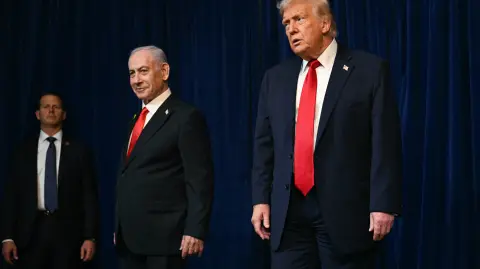 A member of the Secret Service (L) looks on as US President Donald Trump (R) and Israeli Prime Minister Benjamin Netanyahu (C) leave at the conclusion of a joint press conference at Trumps Mar-a-Lago residence in Palm Beach, Florida, on December 29, 2025. US President Donald Trump hosted Israeli Prime Minister Benjamin Netanyahu in Florida on December 29 for crucial talks on moving to the next stage of the fragile Gaza truce plan.The two leaders also discussed Iran, with Trump saying that if Tehran rebuilt its nuclear facilities the United States would "knock them down." (Photo by Jim WATSON / AFP)