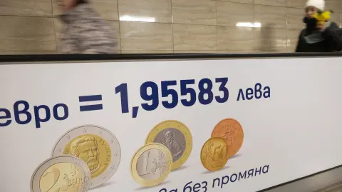 Commuters walk along a moving walkway in Sofia's subway beside an advertisement promoting Bulgaria's entry into the Eurozone on December 31, 2025, ahead of the country's adoption of the euro on January 1, 2026. (Photo by Nikolay DOYCHINOV / AFP)