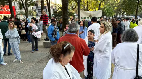 Personas esperan afuera de sus edificios en la CDMX tras evacuar por el sismo.