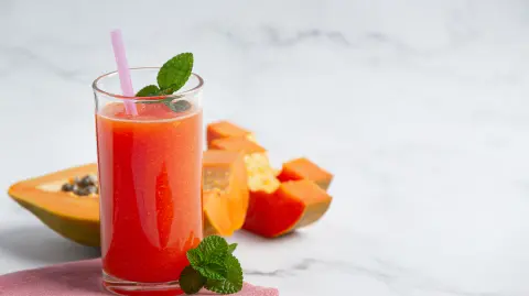 a glass of papaya juice put on white marble floor