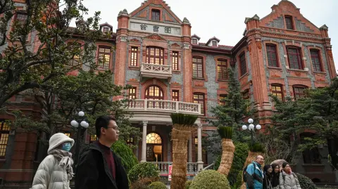 La gente pasa frente a una biblioteca en la Universidad Jiao Tong de Shanghái.