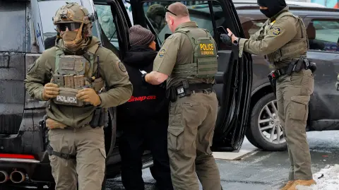 Agentes de la Patrulla Fronteriza de EU detienen a un hombre en la acera.