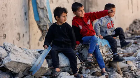 Niños palestinos desplazados se sientan sobre los escombros de un edificio destruido, en la ciudad de Gaza.