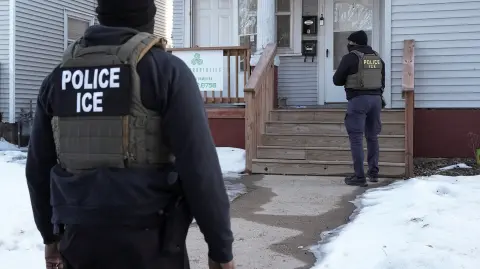 Agentes federales se encuentran afuera de una casa durante una redada de inmigración, días después de que un agente de ICE disparara fatalmente a Renee Nicole Good, en Minneapolis, Minnesota. Imagen del 13 de enero de 2026.