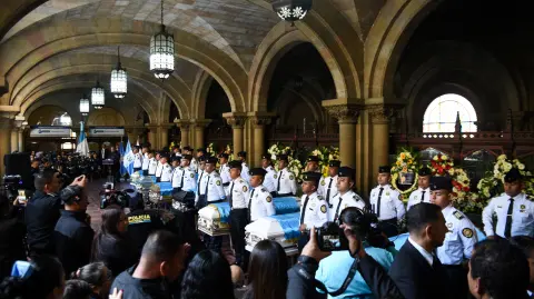 Police officers of Guatemala’s National Civil Police stand next to the flag‑draped caskets of fellow officers during a funeral ceremony, after gang members carried out attacks on security forces, following a series of prison riots and hostage‑takings that triggered an outbreak of violence against police, leaving dead and several wounded, at the Interior Ministry building in Guatemala City, Guatemala, January 19, 2026. REUTERS/Cristina Chiquin