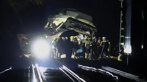 Firefighters and rescue personnel work at the site where at least one person died and four were seriously injured when a regional service train collided with a collapsed wall  between Sant Sadurni d'Anoia and Gelida, near Barcelona, early January 21, 2026. The latest incident is likely to raise more questions about Spanish rail safety after the collision of two high-speed trains in the southern region of Andalusia on Sunday killed 42 people and injured more than 120.  (Photo by Josep LAGO / AFP)