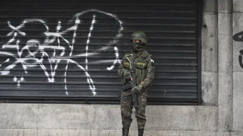 A soldier guard in the historic center during the first day of a state of emergency declared by the government in Guatemala City on January 19, 2026. Guatemala's president on July 18 declared a 30-day nationwide state of emergency to combat criminal gangs after authorities accused the groups of killing eight police officers and holding hostages at three prisons. The killings occurred in the Guatemalan capital and surrounding areas a day after gang-affiliated inmates took 46 people hostage in the three prisons across the country to demand incarcerated gang leaders be moved to lower-security facilities. (Photo by JOHAN ORDONEZ / AFP)