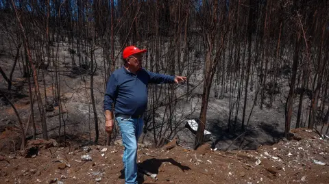 Jorge Cuadra shows a burnt area after the devastating forest fires that ravaged the region on January 3, in Punta de Parra, near Concepcion, Chile, on January 21, 2026. Police in south-central Chile have arrested a man on suspicion of starting one of the recent wildfires that killed 20 people and razed entire neighborhoods, the government said on January 21. (Photo by Raul BRAVO / AFP)