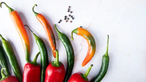 close-up view of peppers and pepper spice on left side and white background with copy space