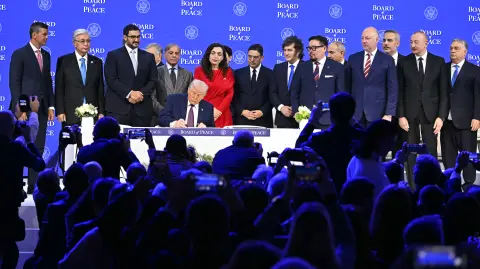 Paraguay's President Santiago Pena (L), Kazakh President Kassym-Jomart Tokayev (2L), Bahrein's Minister of the Prime Minister's court Sheikh Isa bin Salman bin Hamad al-Khalifa (3L), Pakistan's Prime Minister Shehbaz Sharif (4L), Kosovo's President Vjosa Osmani (C-R), Morocco's Foreign Minister Nasser Bourita (8R), Argentina's President Javier Milei (7R), Mongolia's Prime minister Gombojav Zandanshatar (6R), Armenia's Prime Minister Nikol Pashinyan (5R), Bulgaria's former Prime Minister Rosen Zhelyazkov (4R), Turkey's Foreign Minister Hakan Fidan (3R), Azerbaijan's President Ilham Aliyev (2R) and Hungary's Prime Minister Viktor Orban (R) pose with US President Donald Trump (C) signing a founding charter at the "Board of Peace" meeting during the World Economic Forum (WEF) annual meeting in Davos on January 22, 2026. US President Donald Trump will show off his new "Board of Peace" at Davos on January 22, 2026 burnishing his claim to be a peacemaker a day after backing off his own threats against Greenland. Originally meant to oversee the rebuilding of Gaza after the war between Hamas and Israel, the board's charter does not limit its role to the Strip, and has sparked concerns that Trump wants it to rival the United Nations. (Photo by Fabrice COFFRINI / AFP)