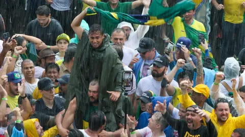 Brazilian Federal Deputy Nikolas Ferreira gestures among supporters of former President Jair Bolsonaro during a march in Brasilia on January 25, 2026. Deputy Ferreira and Bolsonaro's supporters arrived after walking the route between Paracatu, in Minas Gerais state, and the federal capital with the aim of drawing attention to the defense of amnesty for Bolsonaro and those convicted for the acts of January 8, 2023. (Photo by Sergio LIMA / AFP)