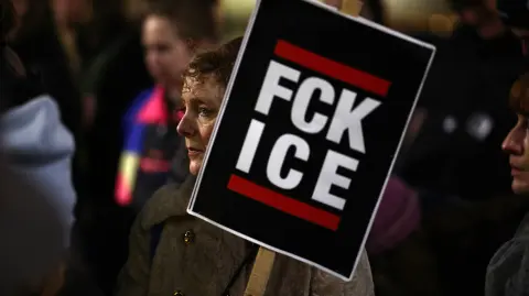 Personas sostienen pancartas durante una vigilia en memoria de Alex Pretti.