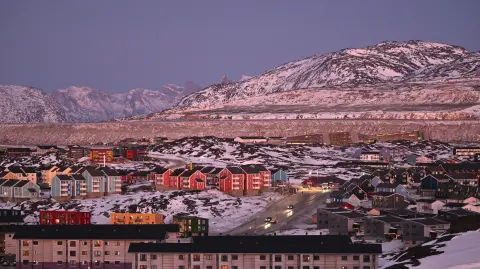 A photo shows a residential area near the airport at the city of Nuuk, western Greenland, with a slightly snow covered mountain in the background, on January 28, 2026. (Photo by Ina FASSBENDER / AFP)