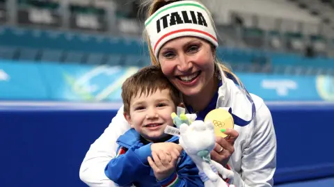 La medallista de oro Francesca Lollobrigida, de Italia, celebra con su hijo tras la ceremonia de la victoria.