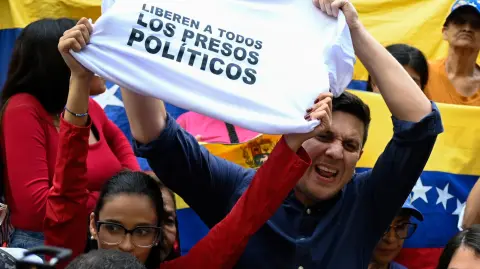 El opositor venezolano Jesús Armas sostiene una camiseta que dice "Liberen a todos los presos políticos".