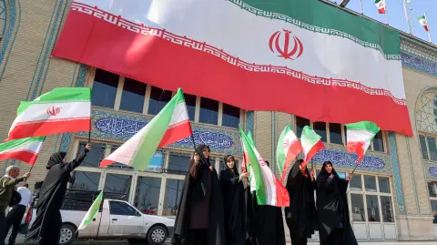 Mujeres ondean banderas iraníes durante una ceremonia conmemorativa en el Musalla de Teherán, el 17 de febrero de 2026.