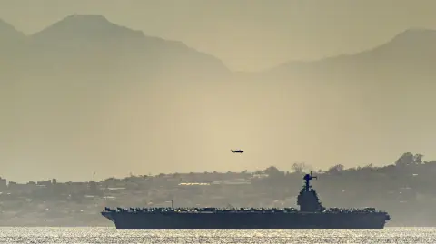 This handout image released and taken by David Parody on February 20, 2026, shows the US aircraft carrier USS Gerald Ford heading through the Strait of Gibraltar as seen from Gibraltar. (Photo by David PARODY / DM Parody / AFP) / RESTRICTED TO EDITORIAL USE - MANDATORY CREDIT "AFP PHOTO / DM PARODY / DAVID PARODY- HANDOUT - NO MARKETING NO ADVERTISING CAMPAIGNS - DISTRIBUTED AS A SERVICE TO CLIENTS
