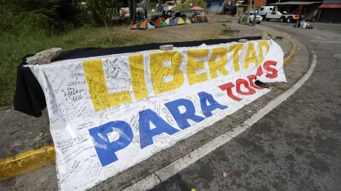 A banner reading "Freedom for all" is displayed in front of El Rodeo I prison in Guatire, Miranda state, Venezuela, on February 20, 2026. Venezuela's National Assembly on February 19 unanimously approved a long-awaited amnesty law that could free hundreds of political prisoners jailed for being government detractors. (Photo by Pedro MATTEY / AFP)